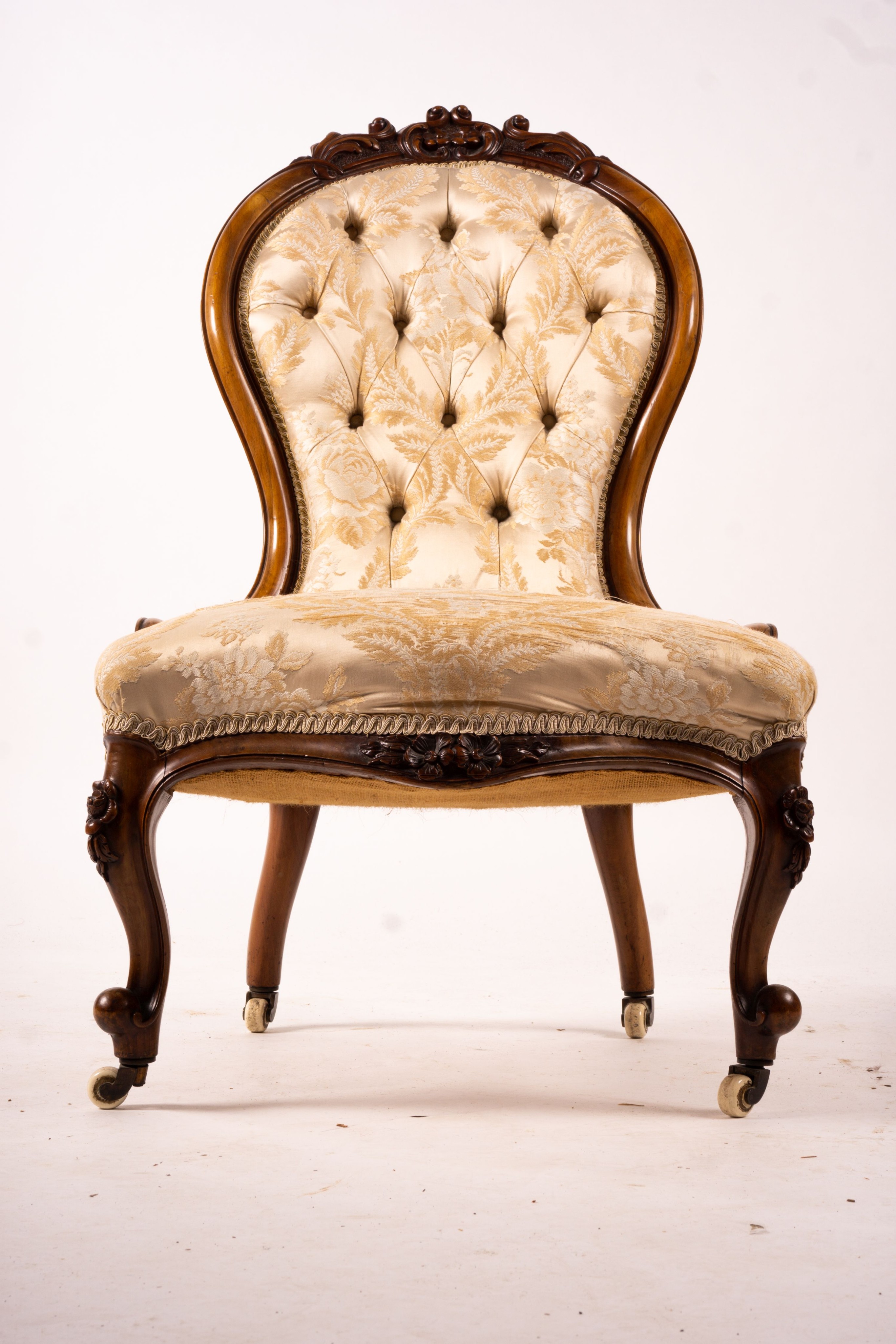 A late Victorian carved walnut three piece salon suite, comprising chaise longue, open armchair and nursing chair